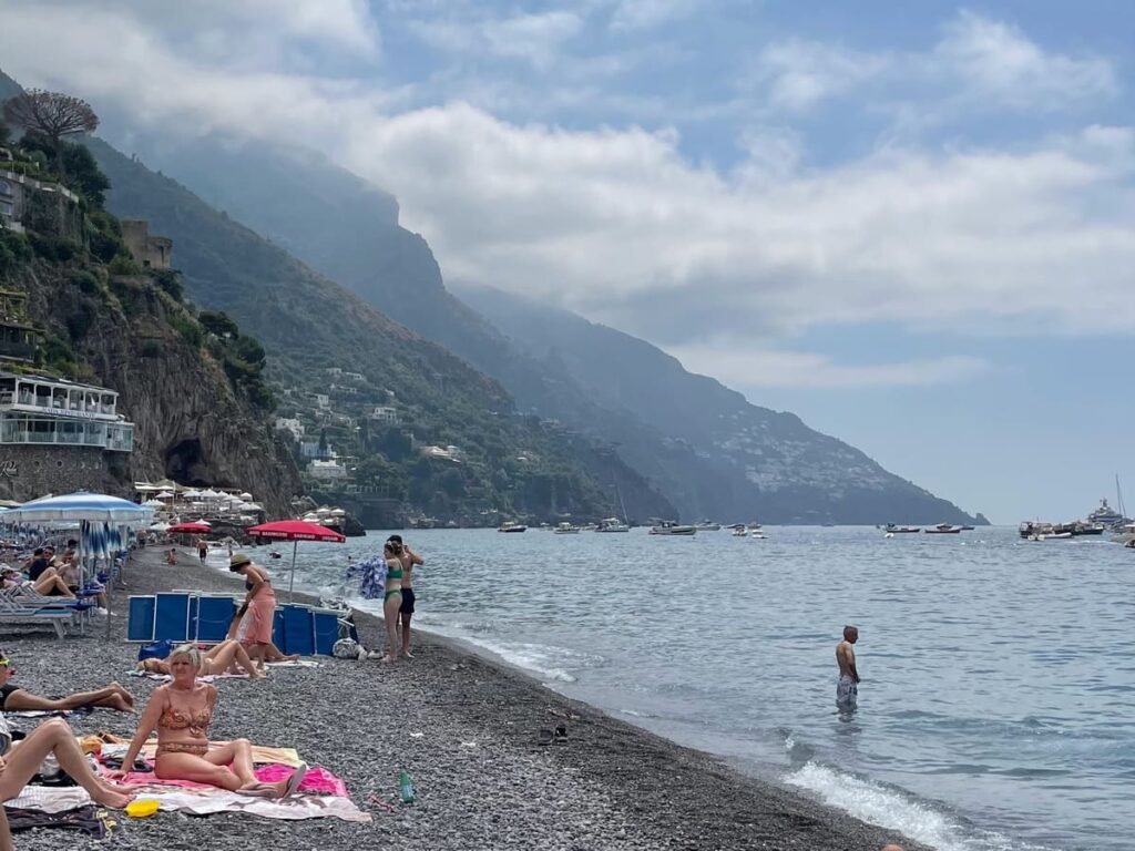 Vista da praia Spiaggia Grande, em Positano. Pedras no lugar de areia e um azul escuro no mar.